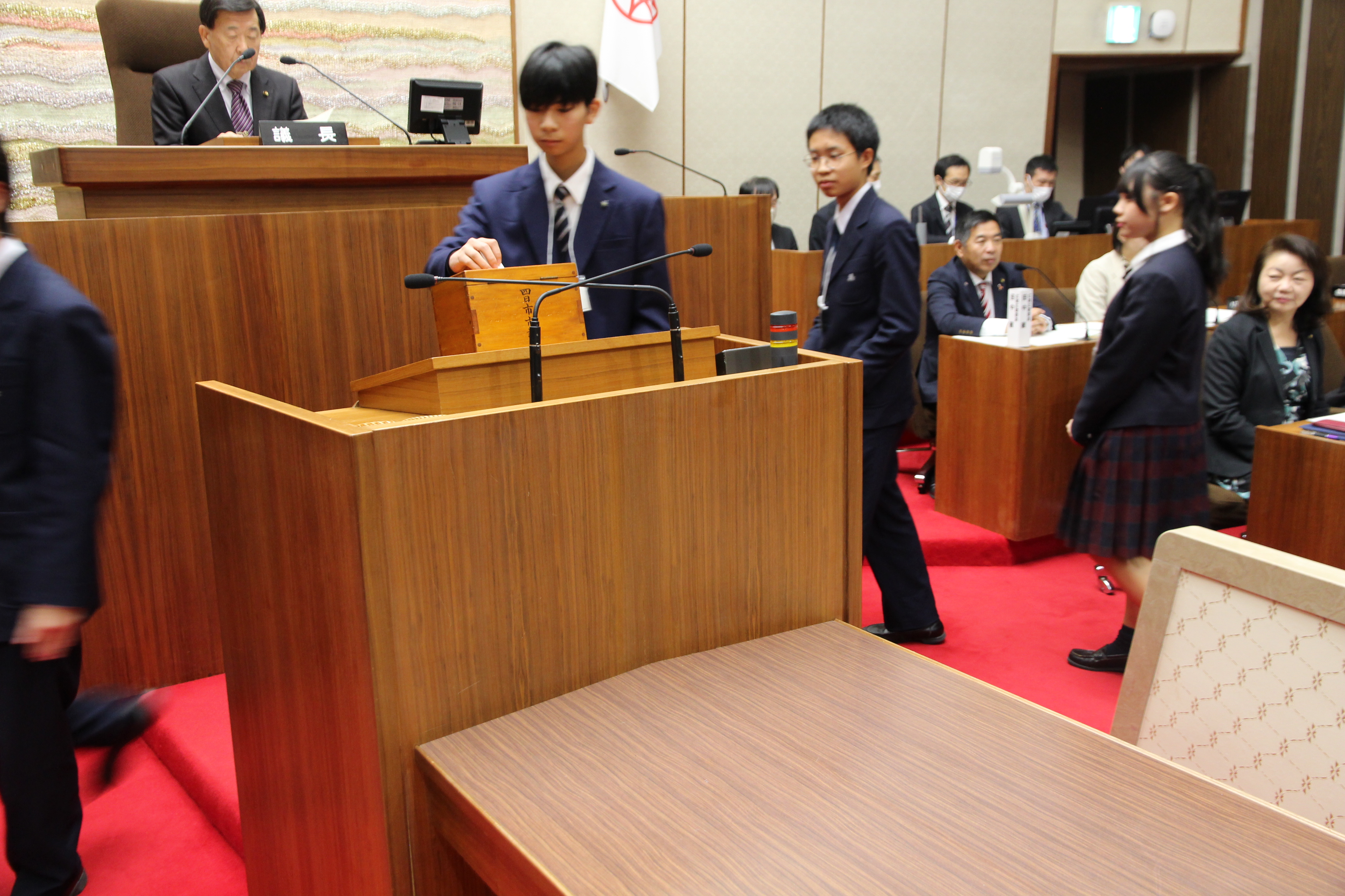 列になり投票箱へ投票する高校生議員